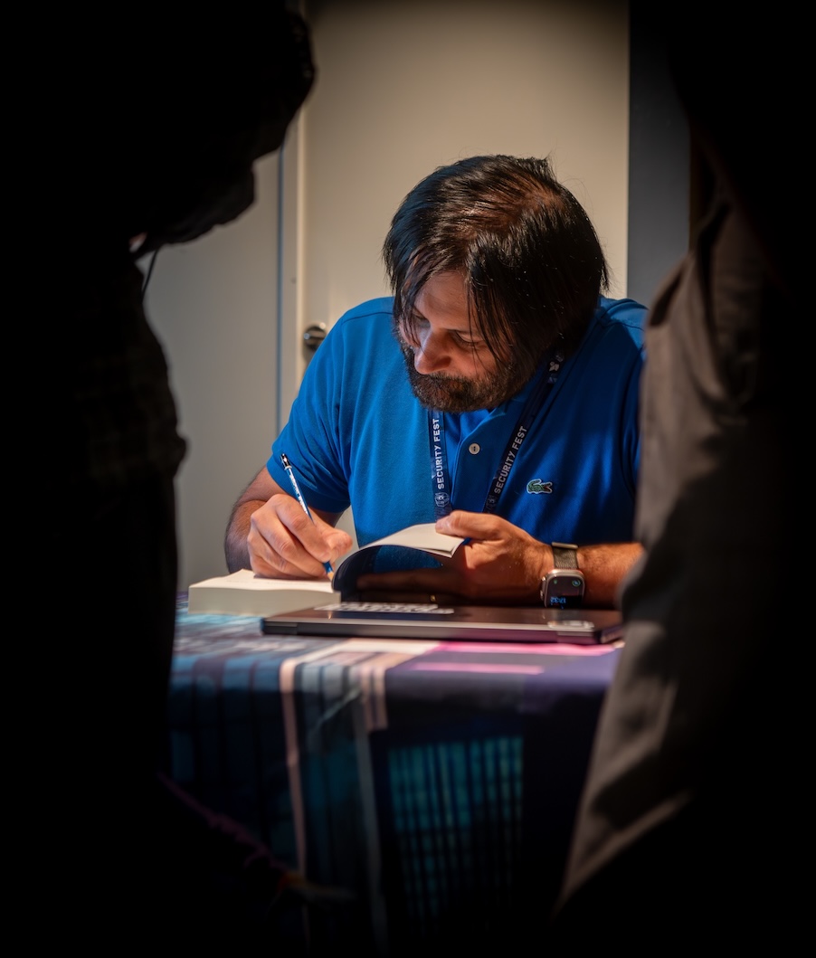 John at the signing table, signing a book.