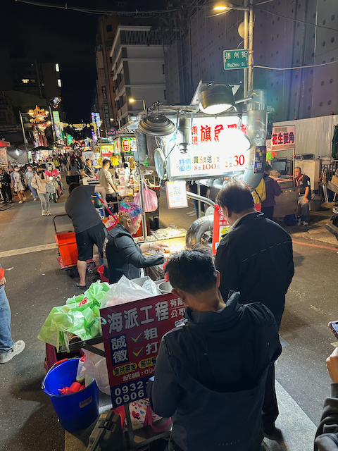 Photo of Taiwan tempura food stand at the night market. The lady running the show has her short, wavy hair colored in pink, magenta, and turquoise.