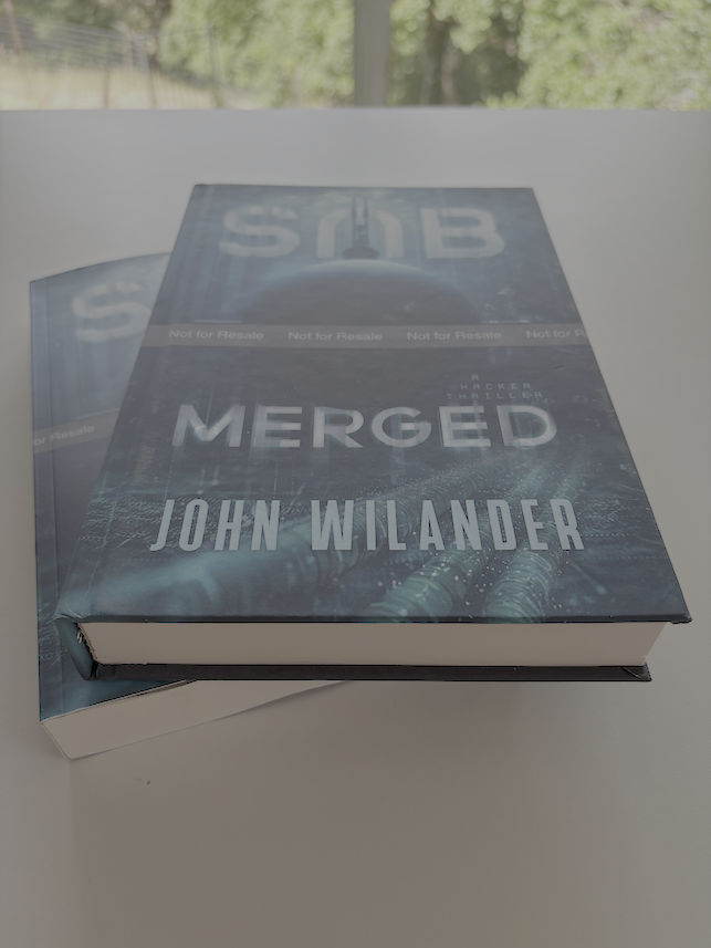 Two proof copies of the novel Submerged stacked on a white desk, paperback at the bottom and hardcover on top.