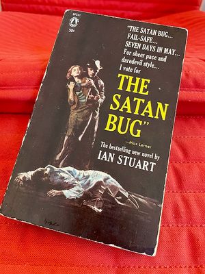 Vintage paperback copy of the novel The Satan Bug. The cover features a dead man in a white trenchcoat lying in front. Behind it a man in a hat holds a woman in a dress and the woman is trying to get out of his grip.